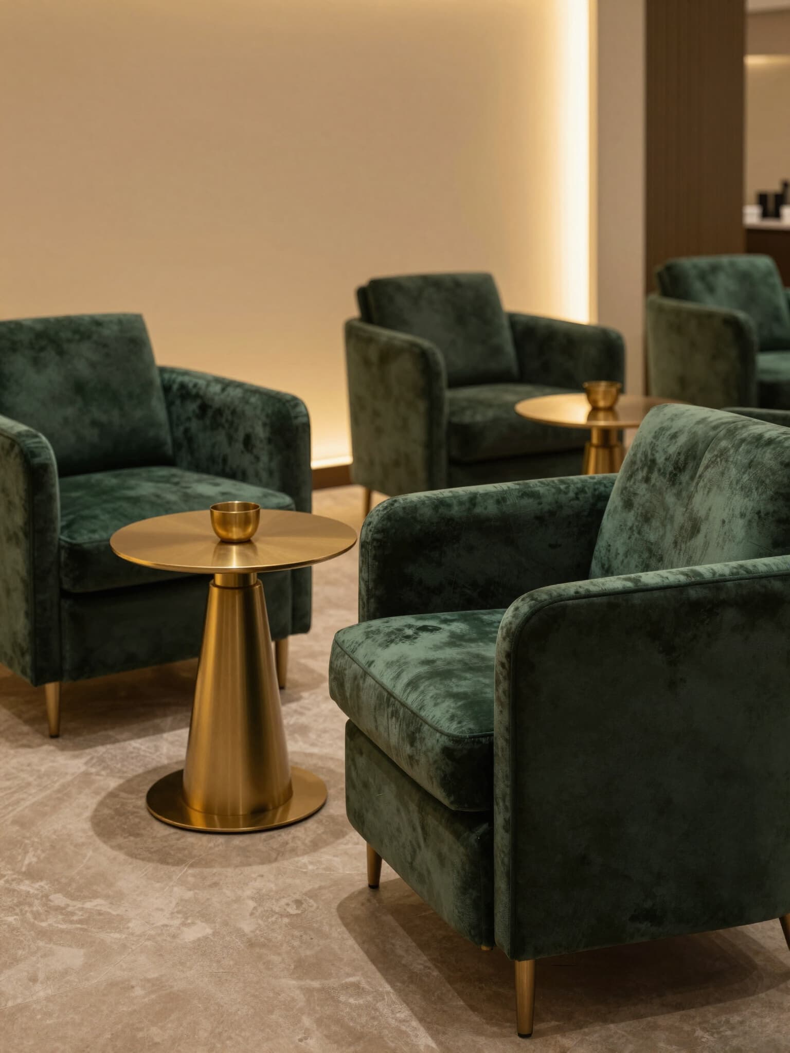 A private lounge with green velvet chairs and brass tables